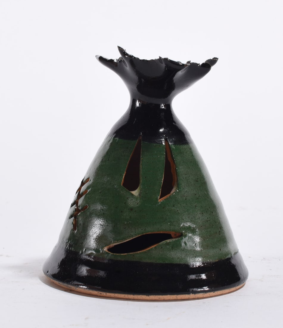 Southern Pottery Face Jug Lantern, Green and Black Glaze: 20th century. Hand-thrown and cut earthenware vessel with elongated eye and mouth openings. Two-tone green and black glaze with flared rim. Reflects the face jug tradition found in Southern alkaline a