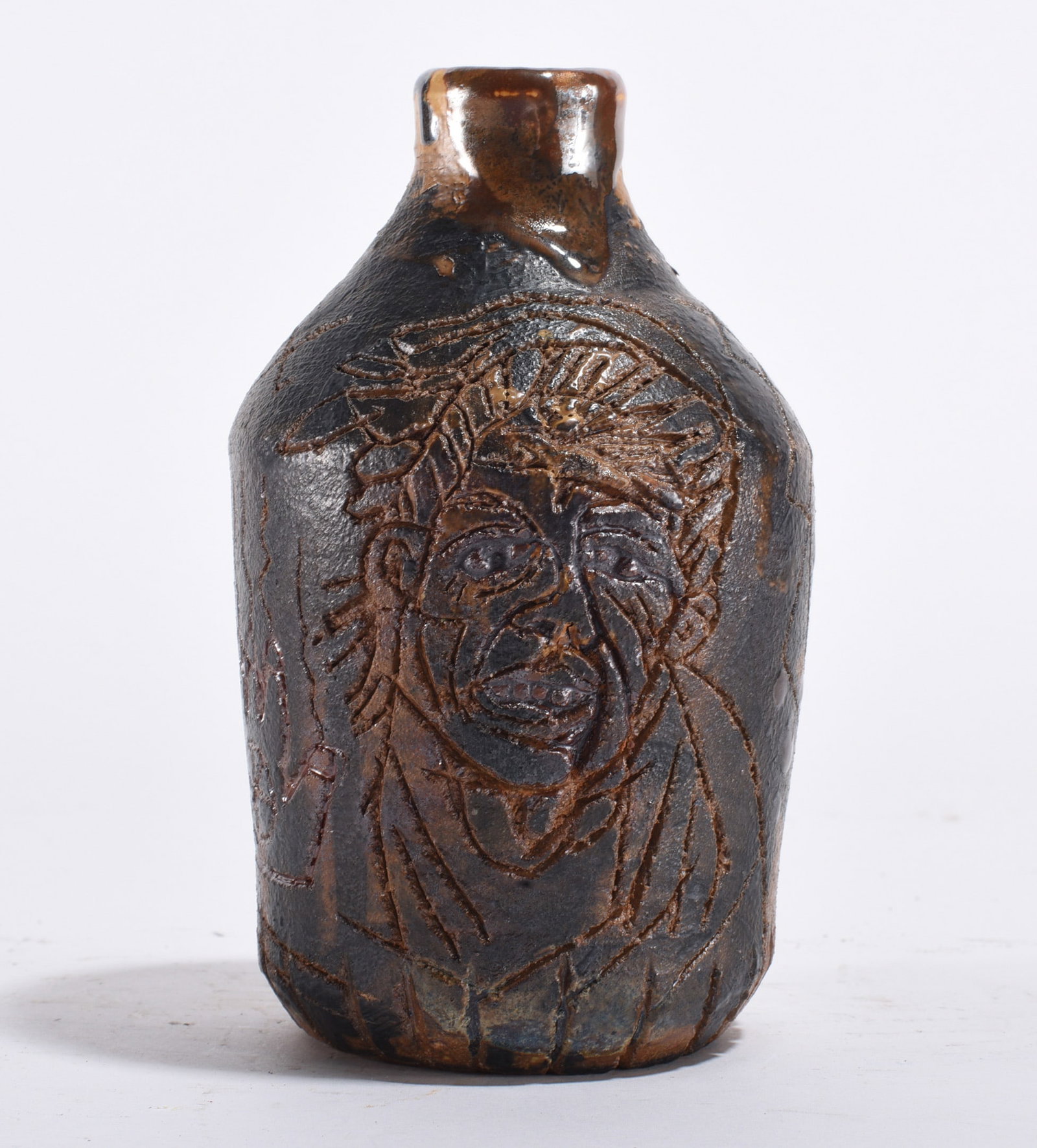 Folk Art Carved Face Jug, Dark Glaze: 20th century. Hand-built stoneware jug with incised portrait decoration. Dark glaze highlights carved facial features in a manner consistent with modern interpretations of the Southern face jug tradit