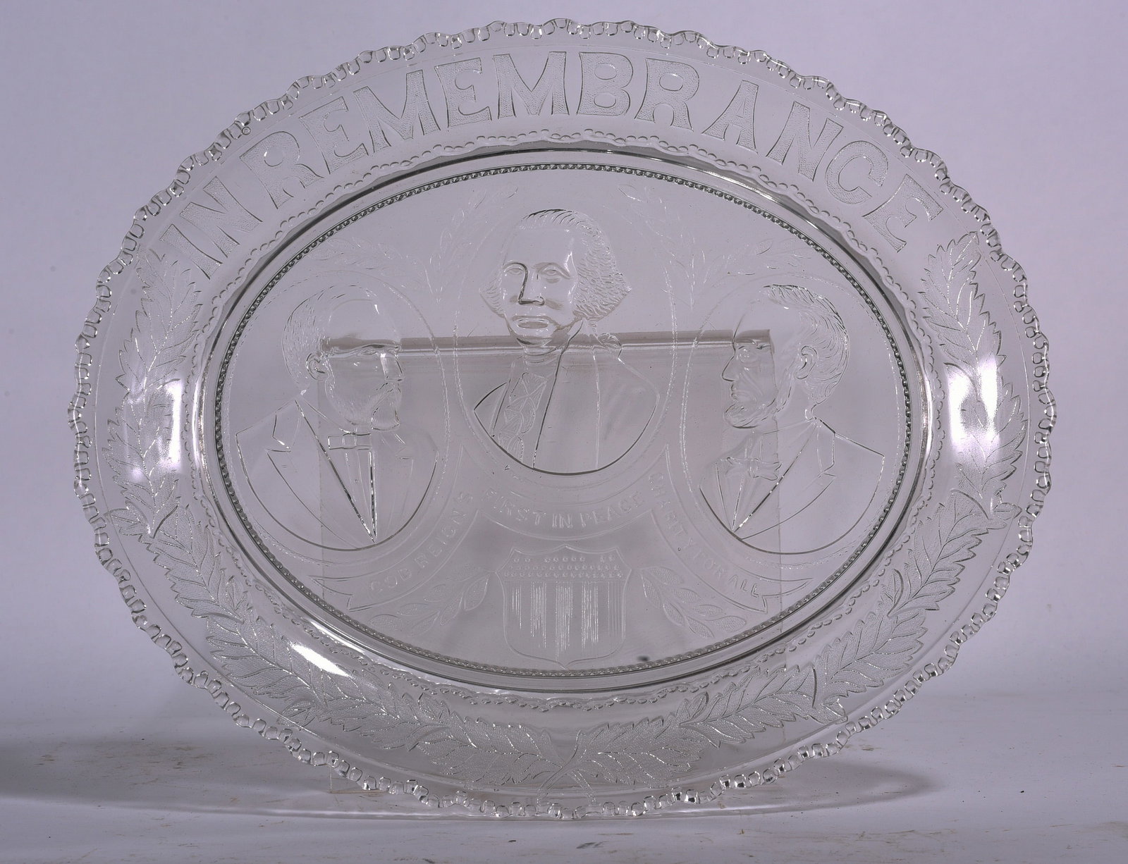 “Min Remembrance?? Glass Plate: Pressed glass commemorative plate featuring three portrait medallions and patriotic motifs. Likely early 20th century American commemorative piece.