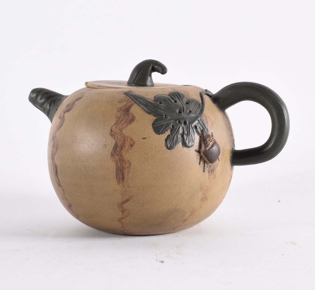 Studio Pottery Teapot with Applied Leaf Decoration: 3" Studio pottery teapot with rounded body, naturalistic glaze, and applied decoration of leaves and insect motif. Features contrasting dark handle and spout. Likely late 20th century artisan piece.