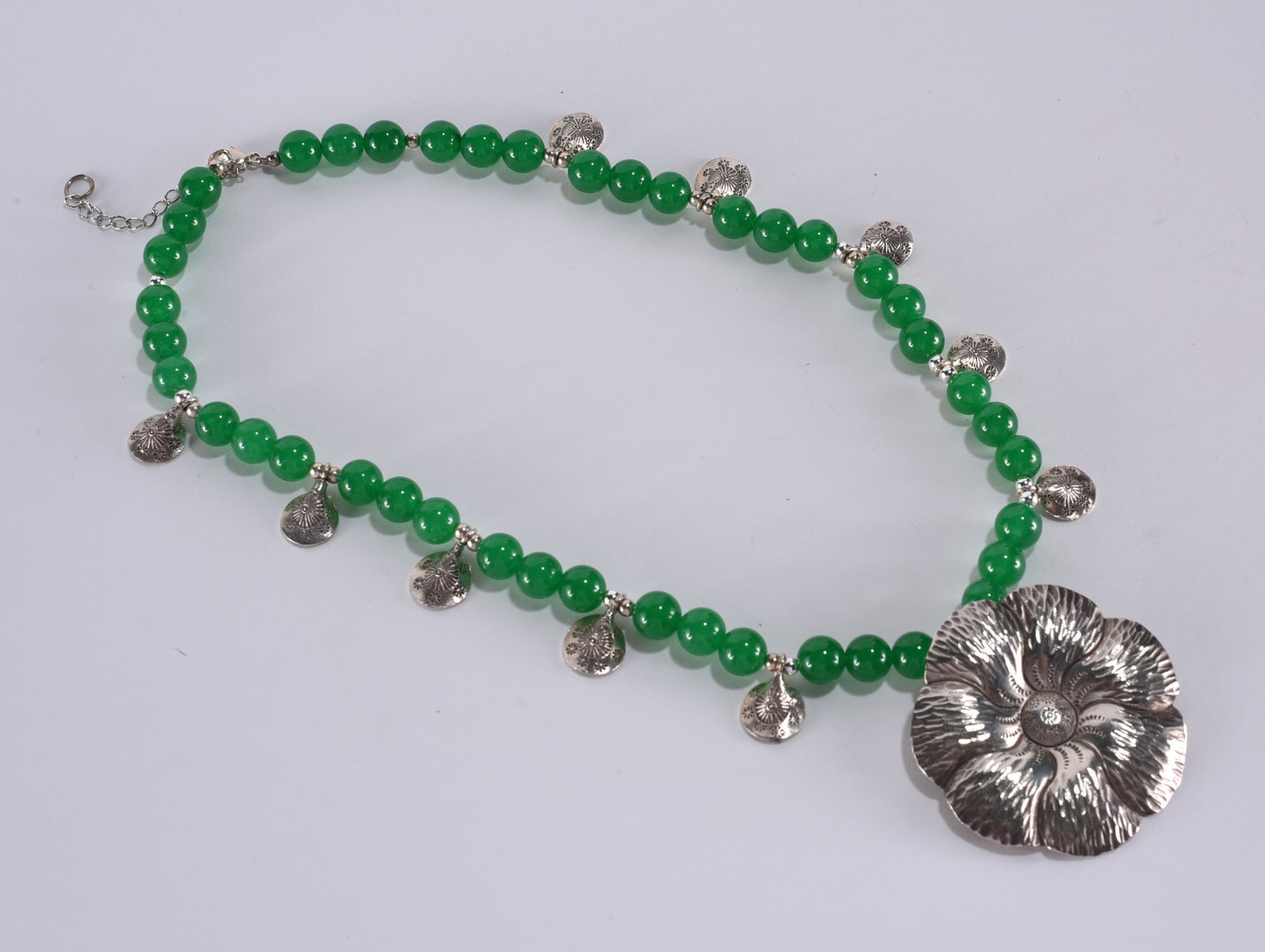 Green agate beaded necklace with silver tone center flower and floral spacers. Sterling Silver: Green agate beaded necklace with silver tone center flower and floral spacers. Sterling Silver clasp. 16"