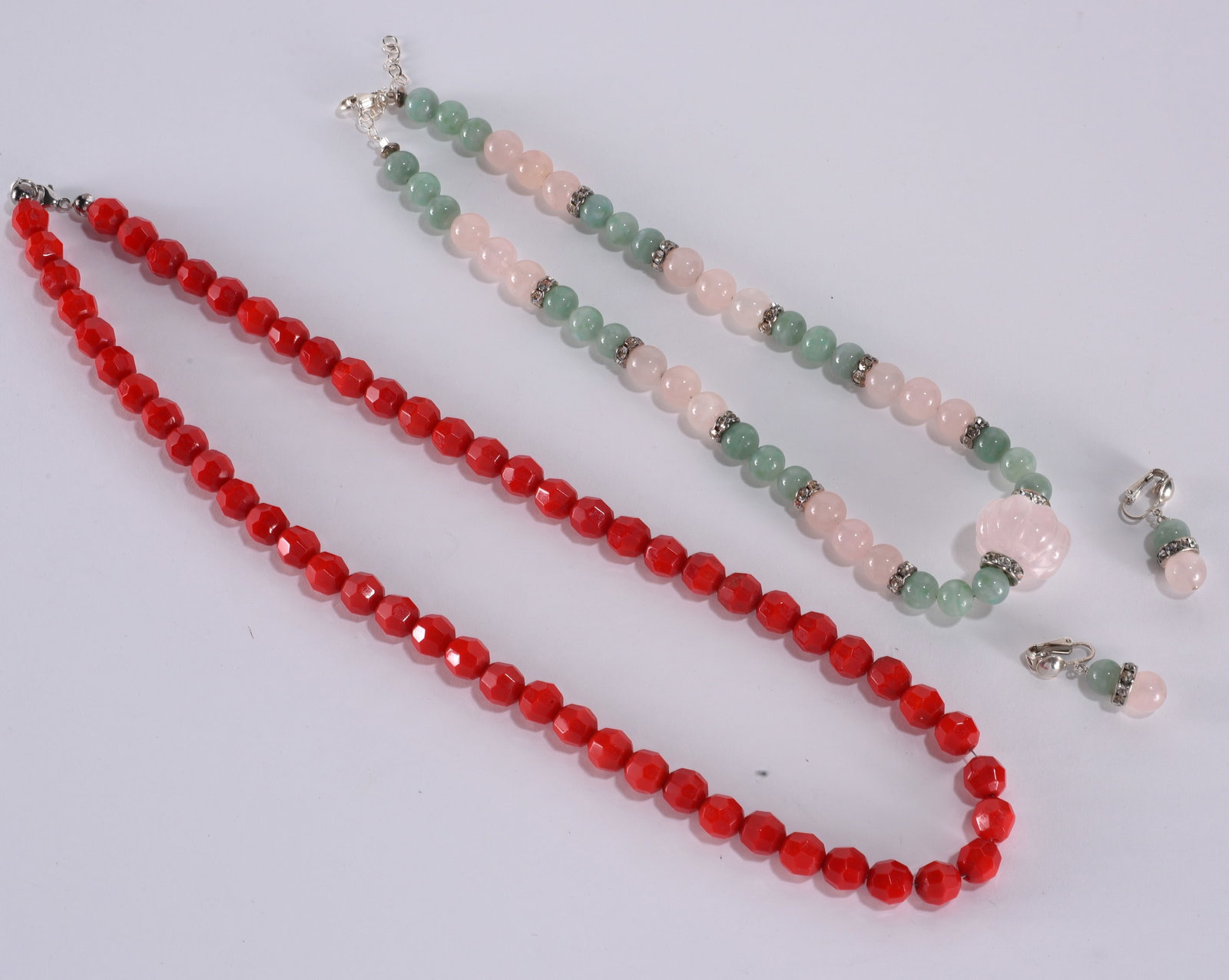 Faceted red beaded necklace. Sterling Silver clasp. 22"?plus; Carved rose quartz pendant. With: Faceted red beaded necklace. Sterling Silver clasp. 22"?plus; Carved rose quartz pendant. With light green and rose colored beads with rhinestone spacers. Sterling Silver clasp with clip earrings.
