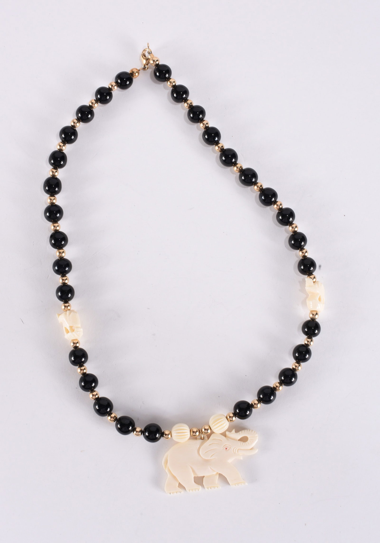 Carved bone elephant pendant on black and gold beaded necklace. Gold filled clasp. 18" (1 of 2)