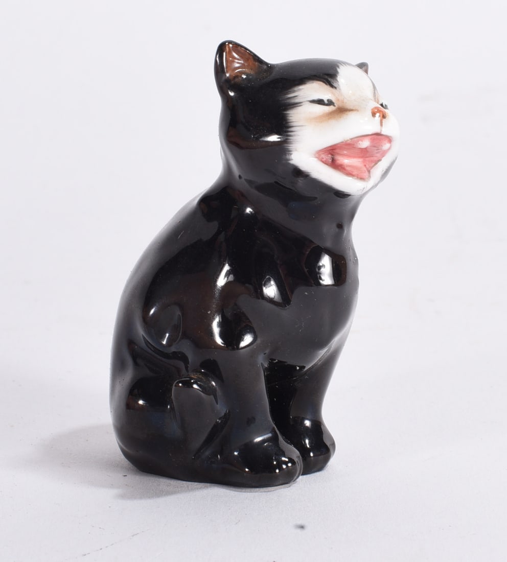 Black Ceramic Laughing Cat Figurine: Glossy black ceramic cat figurine with exaggerated pink mouth and whimsical expression, likely mid-century decorative piece.
