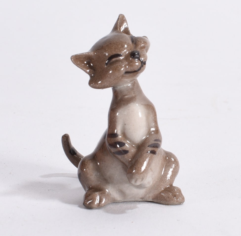 Anthropomorphic Cat Ceramic Figurine: Whimsical ceramic anthropomorphic cat figurine seated upright with smiling expression and folded paws.