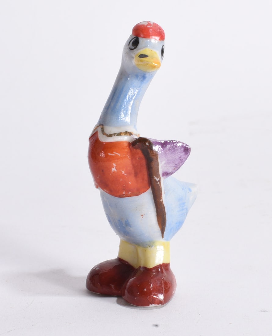 Whimsical Goose Figurine: Colorful ceramic goose figurine dressed in clothing and oversized shoes, whimsical character design.