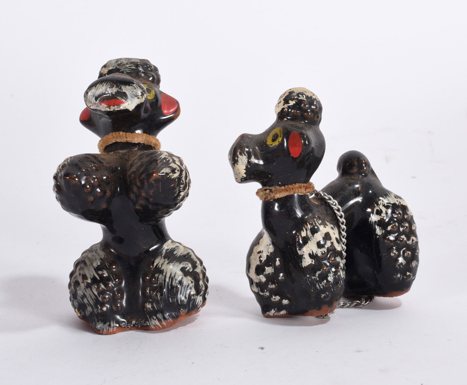 Pair of Black Poodle Figurines: Pair of black poodle figurines with painted decoration, one joined by chain leash accessory.