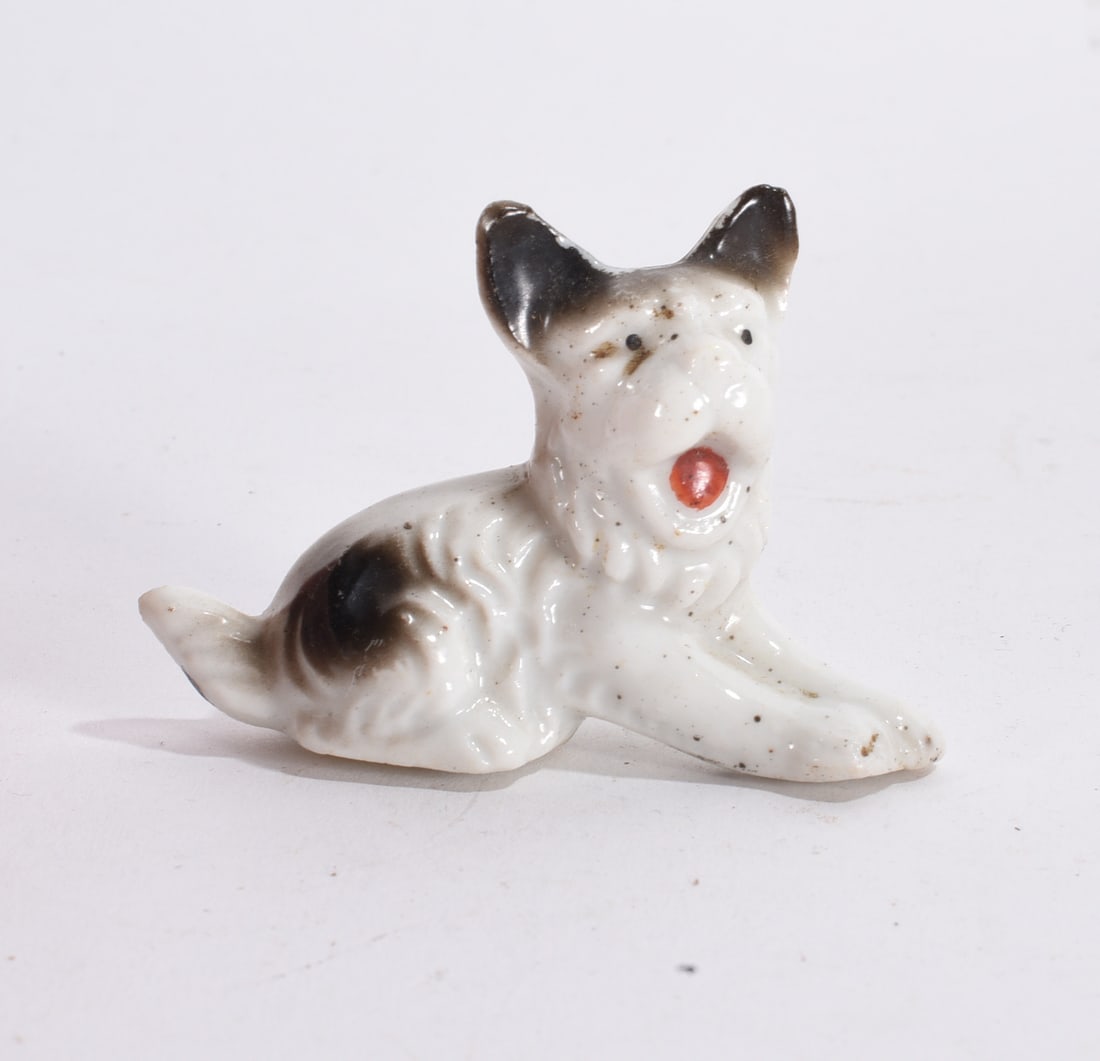 Terrier Dog Figurine: Small ceramic Dalmatian puppy figurine in reclining pose with black ear and red tongue detail.