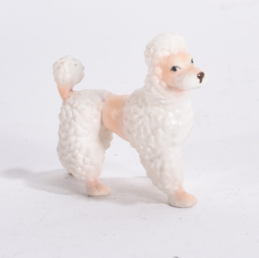White Poodle Figurine: Small white and pink ceramic poodle figurine with textured fur detail and curled tail.
