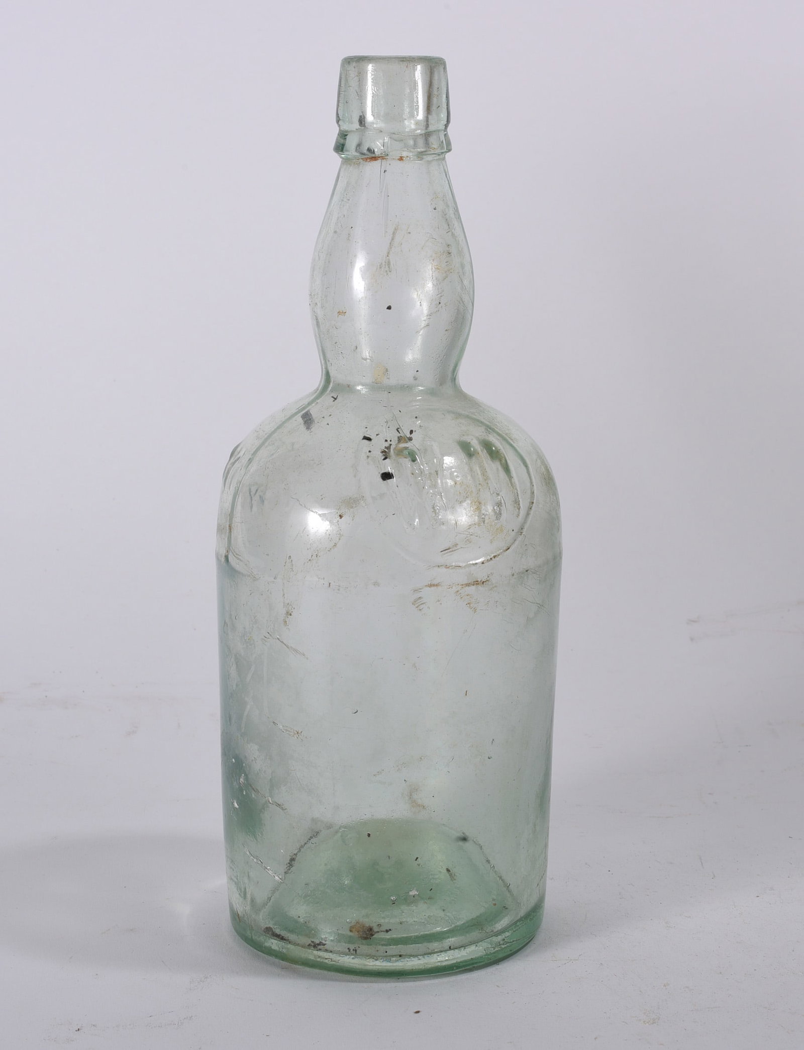 Clear Hutchinson-Type Soda Bottle: Early clear glass soda bottle with rounded shoulder and narrow neck. Surface haze and scratching consistent with age and use.