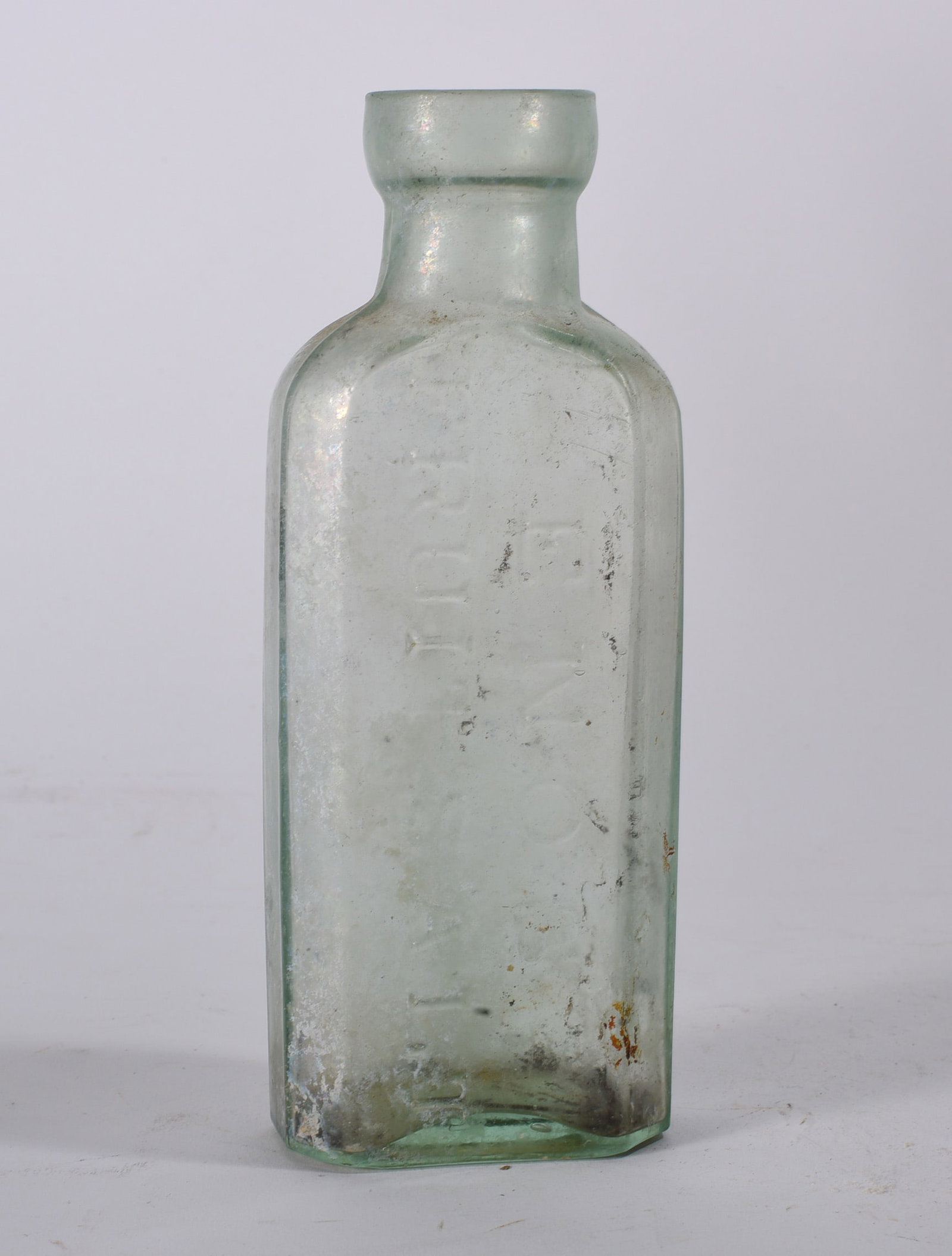 Aqua Embossed Medicine Bottle: Antique aqua medicine bottle with embossed vertical lettering to paneled body. Showing haze, scratches, and mineral staining.