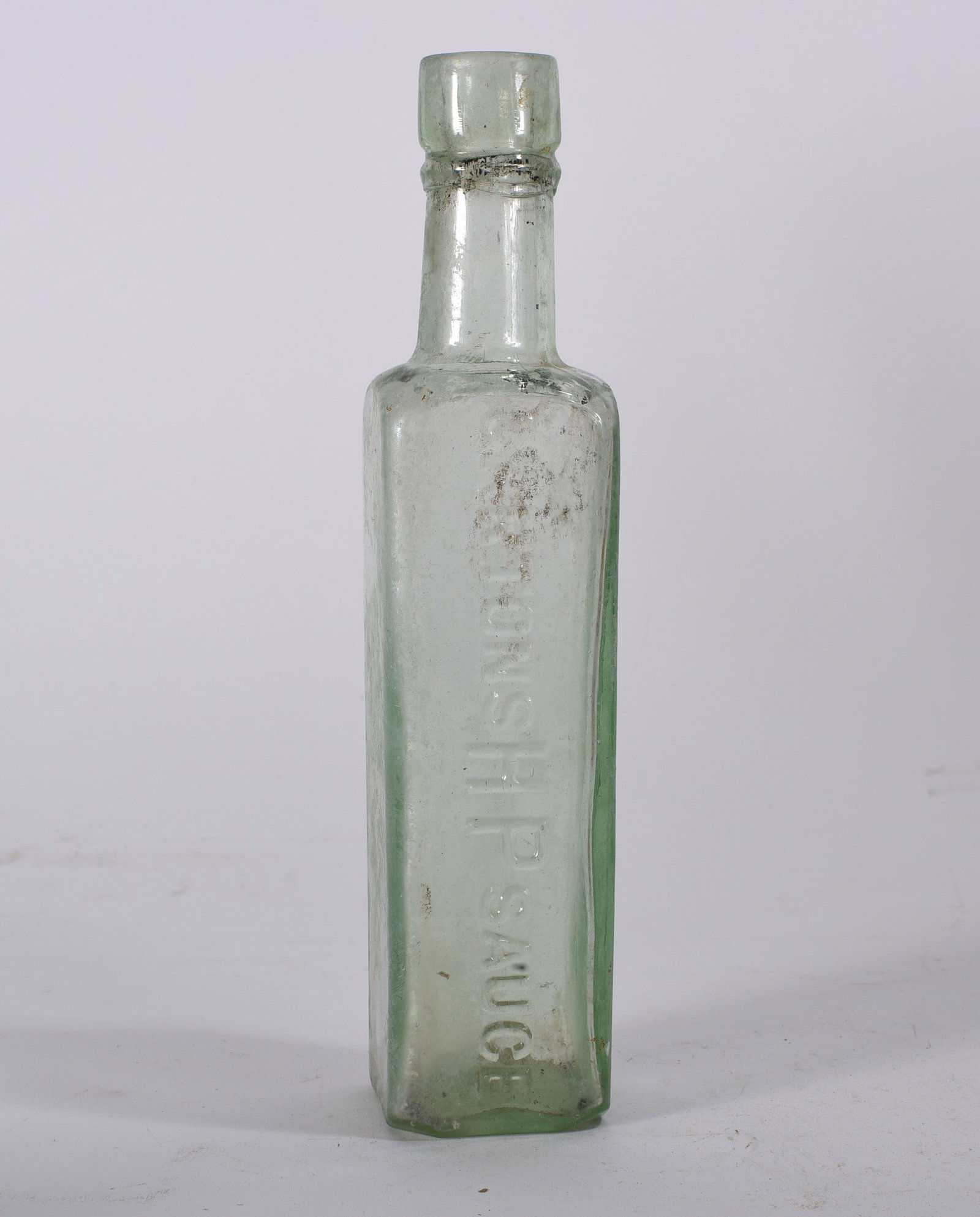 Aqua Rectangular Apothecary Bottle: Early rectangular aqua glass apothecary bottle with broad shoulder and short neck. Visible embossing, interior residue, and weathered surface.