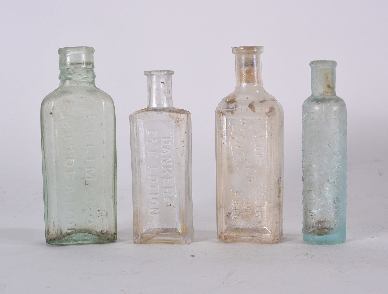 Assorted Antique Medicine Bottle Group: Aqua paneled medicine or pharmacy bottle with embossed lettering and tapered shoulder. Showing dirt inclusions, staining, and age wear.