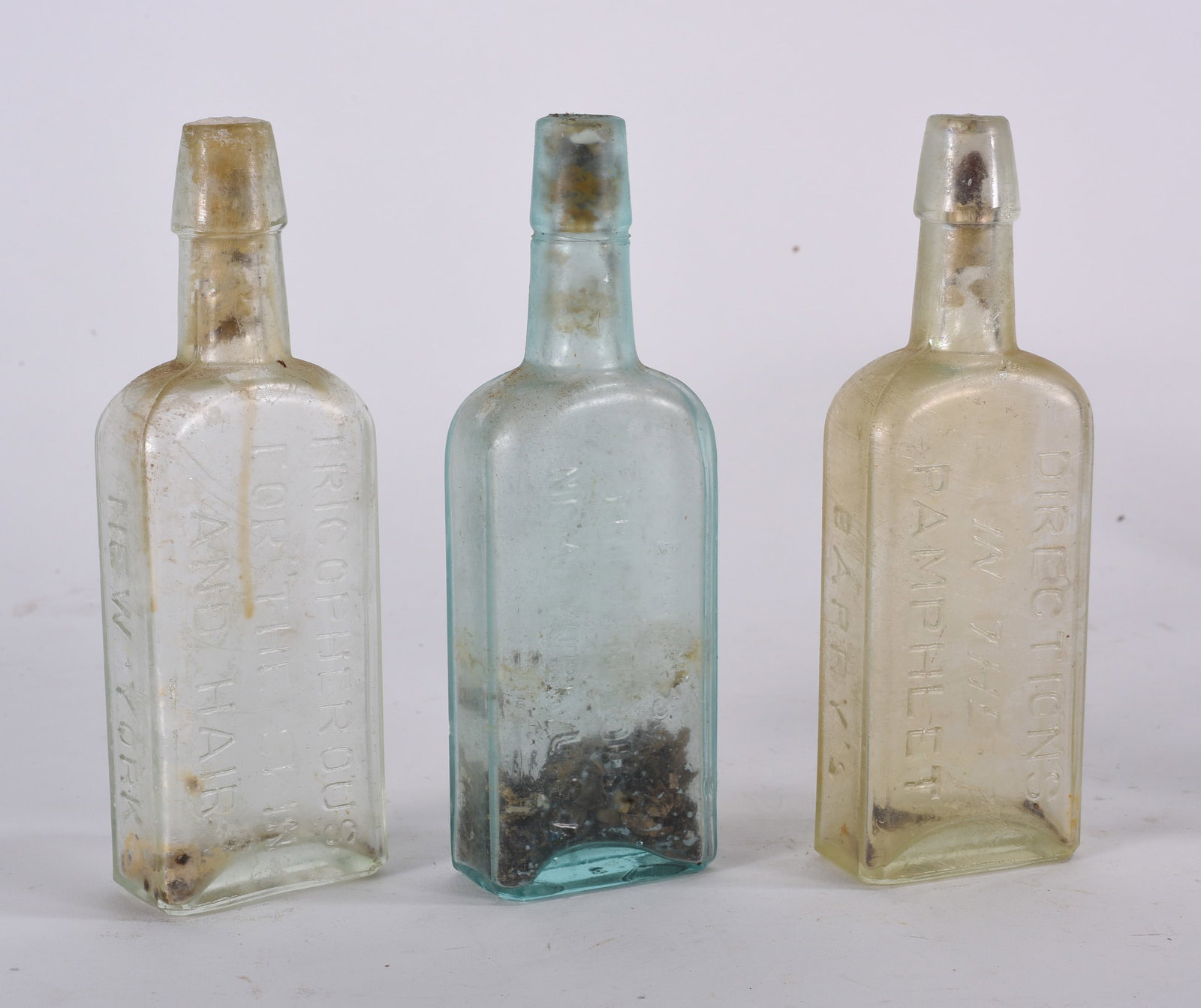 Antique Bottles: Collection of early blown aqua bottles in assorted forms including cylindrical and rectangular examples with age-related staining and residue.