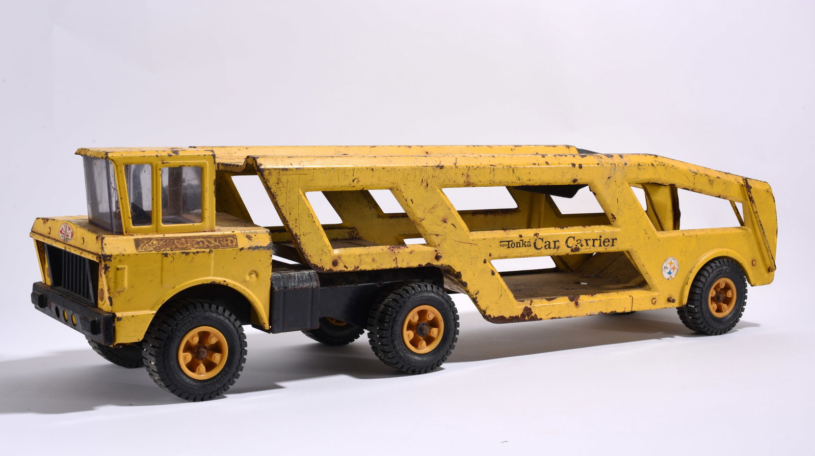 Tonka Pressed Steel Car Carrier Transport Truck: Vintage Tonka pressed steel car carrier transport truck in yellow finish. Features dual-level carrier trailer with original wheels. Surface wear, scratches, and oxidation present.