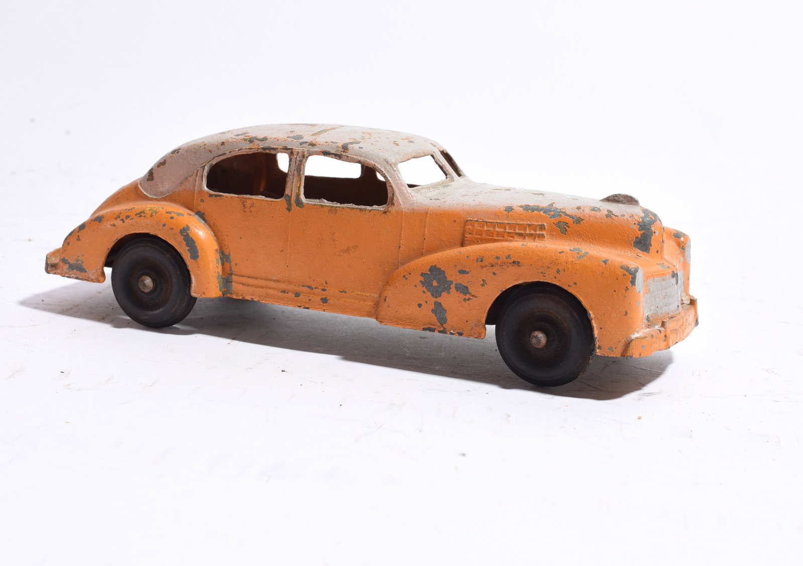Cast Metal Streamlined Sedan Toy Car: Vintage cast metal streamlined sedan toy car with orange paint and silver roof. Features black wheels and Art Deco-inspired styling. Heavy paint wear and surface losses from age and play use.