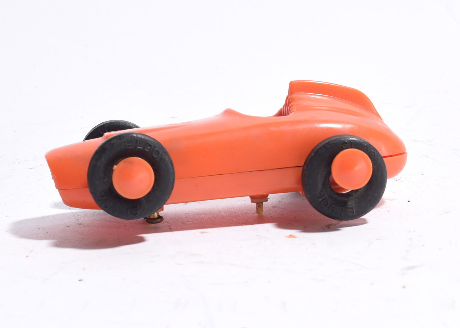 Eldon Open-Wheel Racing Car: Eldon open-wheel racing car in orange plastic. Features large black tires, aerodynamic body styling, and molded driver compartment. Minor wear consistent with age.