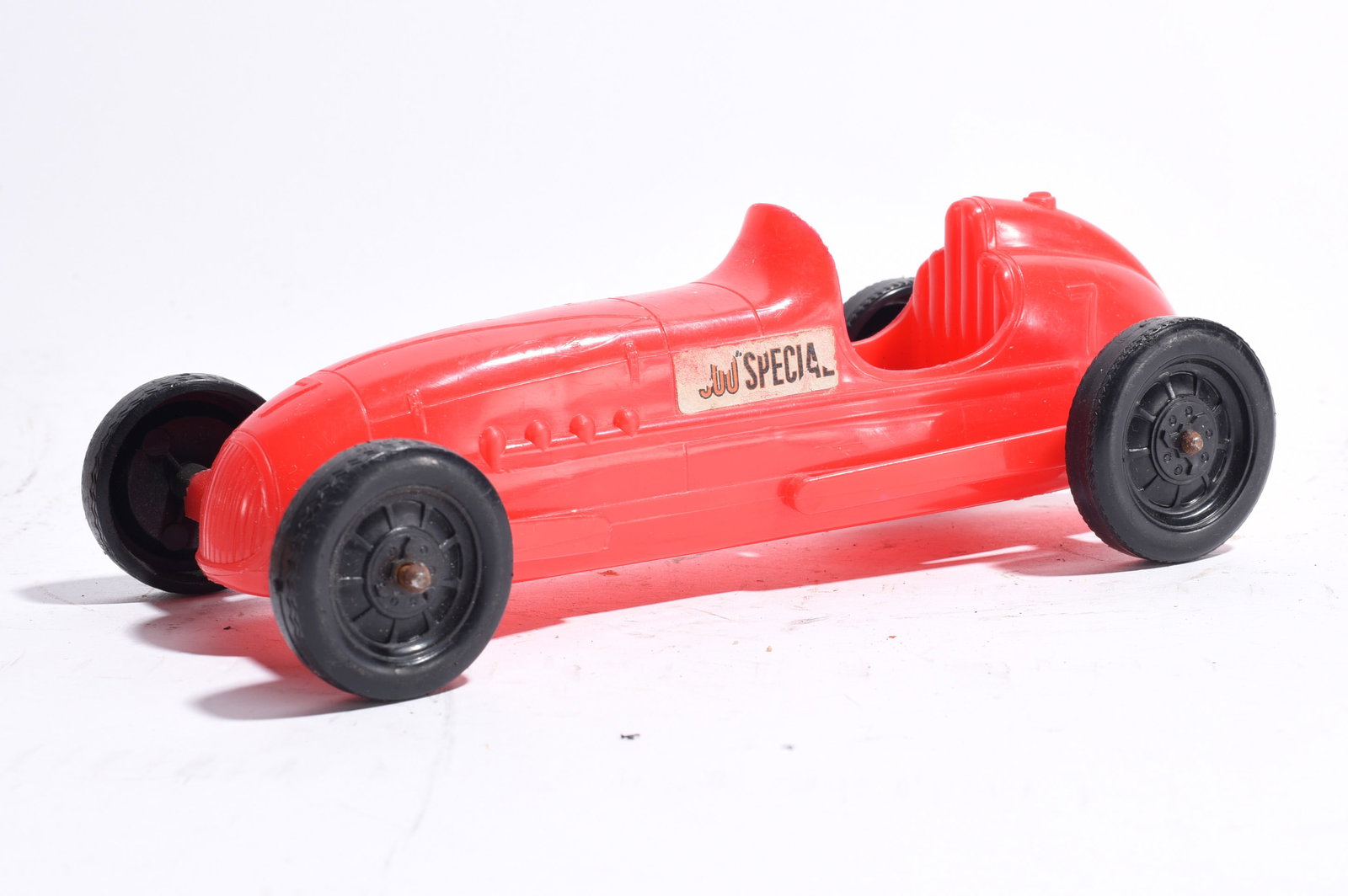 "Juu Special" Open-Wheel Race Car: "Juu Special" plastic racing car with bright red body and black wheels. Open cockpit design with original side decal. Light wear and scattered scuffs noted.
