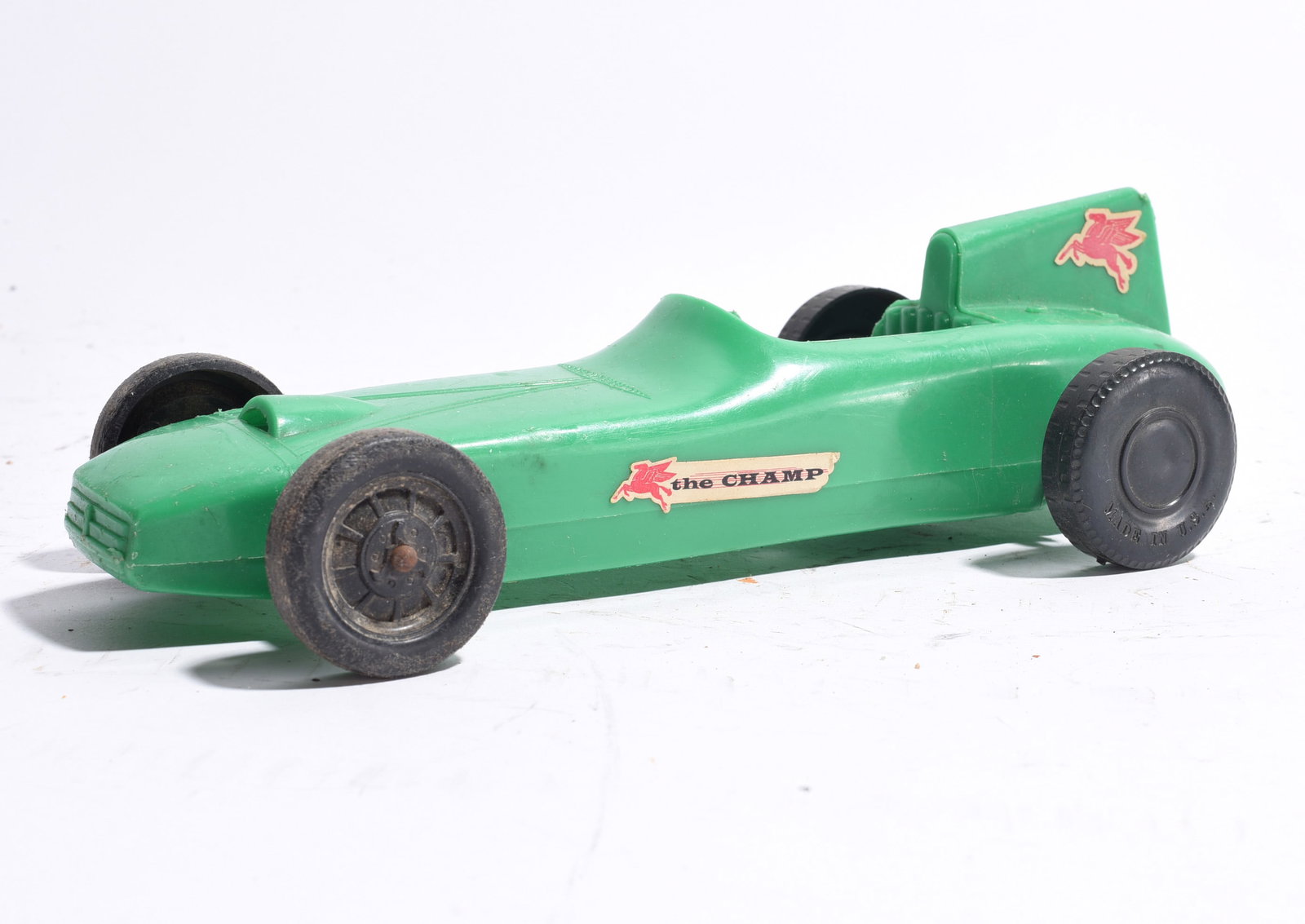 "The Champ" Open-Wheel Racing Car: "The Champ" open-wheel race car in green plastic with original racing decals. Features molded aerodynamic body and black wheels. Good vintage condition with minor play wear.