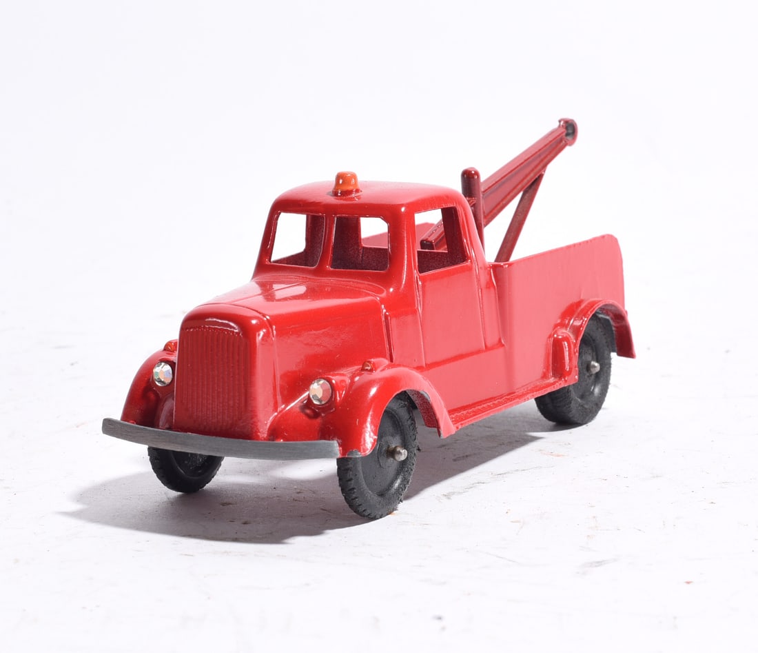 Toy Wrecker Tow Truck: Toy wrecker truck with bright red body, tow boom assembly, and black wheels. Features working-style recovery truck design with roof beacon detail. Appears repainted or restored and presents in very go