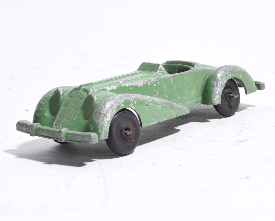Cast Metal Convertible Roadster Toy Car: Cast metal convertible roadster toy automobile in green paint with streamlined prewar styling. Features silver-painted fenders and grille accents with black wheels. Moderate paint wear and surface