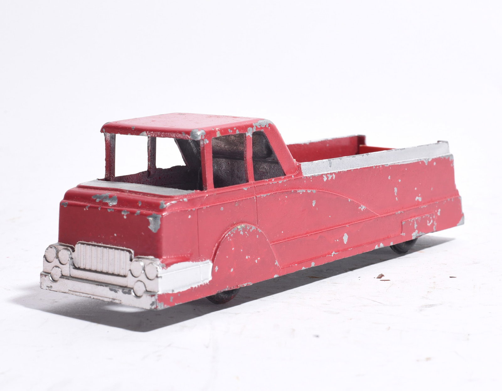 Pressed Steel Stake Bed Truck: Pressed steel stake bed truck finished in red paint with silver-toned bed rails. Displays moderate paint wear, scratches, and age-related surface losses.