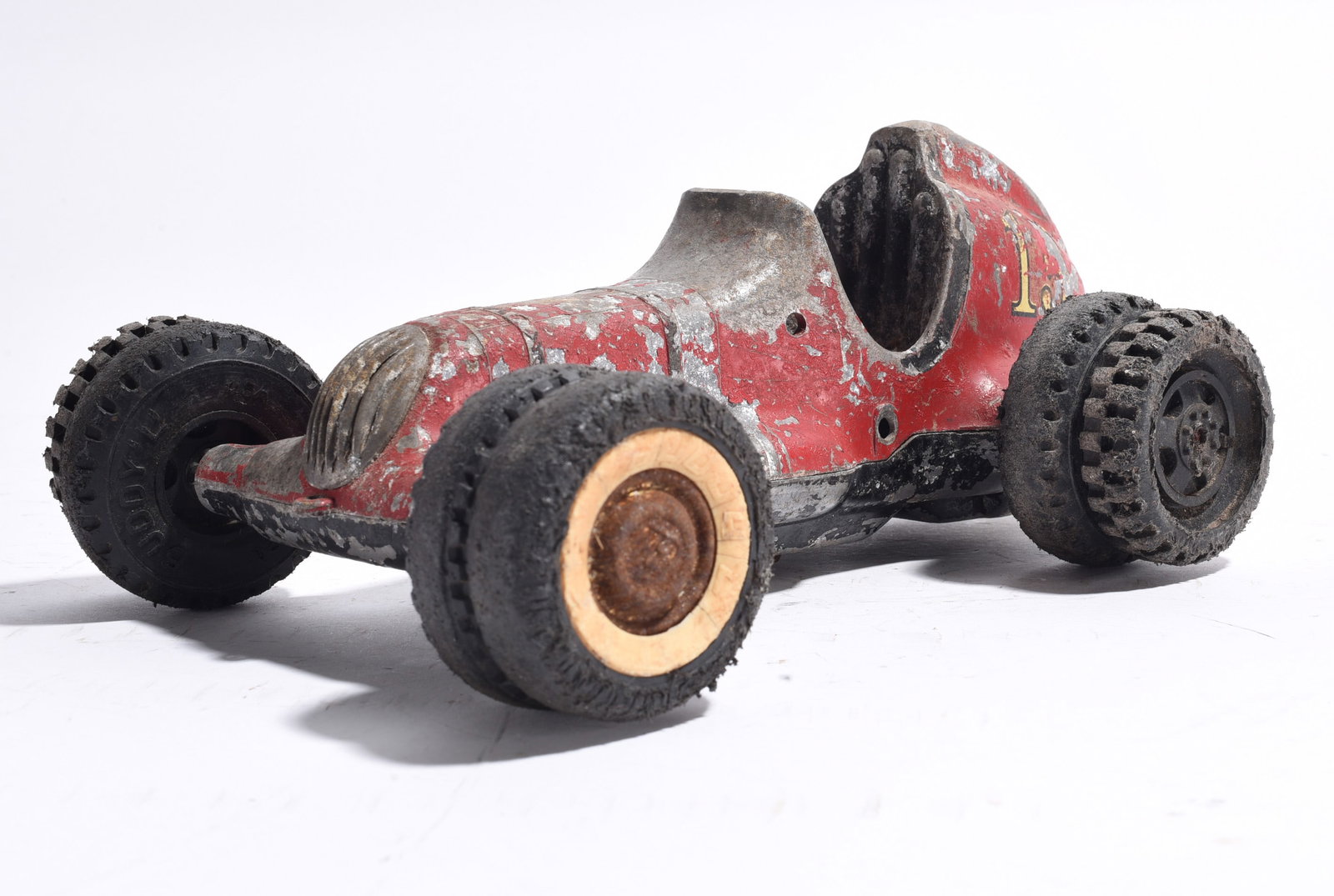 Cast Metal Race Car No. 16: Cast metal race car marked with racing number "16." Finished in red paint with exposed cockpit and oversized rubber tires. Displays heavy paint wear and age-related use.
