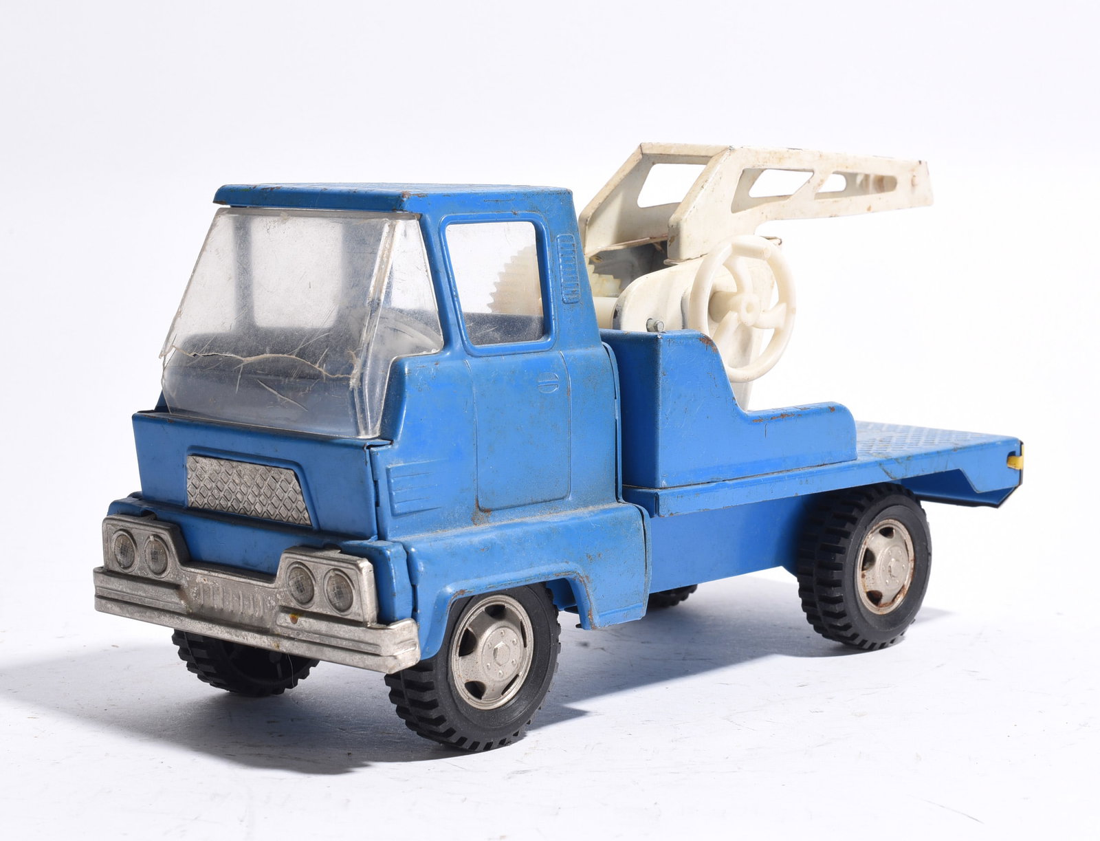 Plastic Wrecker Tow Truck: Plastic wrecker tow truck with blue cab, white towing apparatus, and black wheels. Features clear windshield and molded recovery equipment. Moderate wear from age and use.