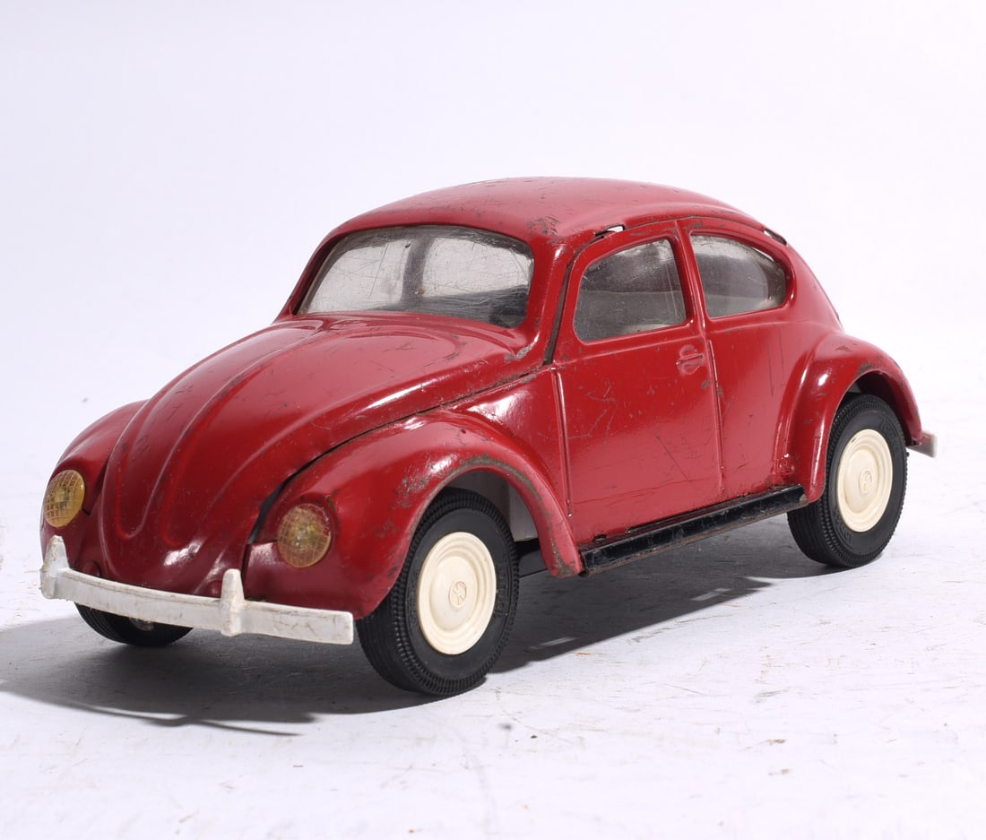 Volkswagen Beetle Tin Toy Automobile: Volkswagen Beetle toy automobile finished in red with cream wheels and clear windows. Features detailed body styling and shows moderate wear from play and age.