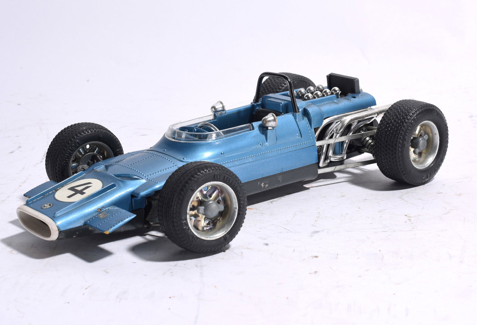 Blue Formula One Style Race Car No. 4: Blue Formula One style race car marked No. 4 featuring exposed engine detail, racing cockpit, and rubber tires. Displays minor wear and remains an attractive vintage racing toy example.