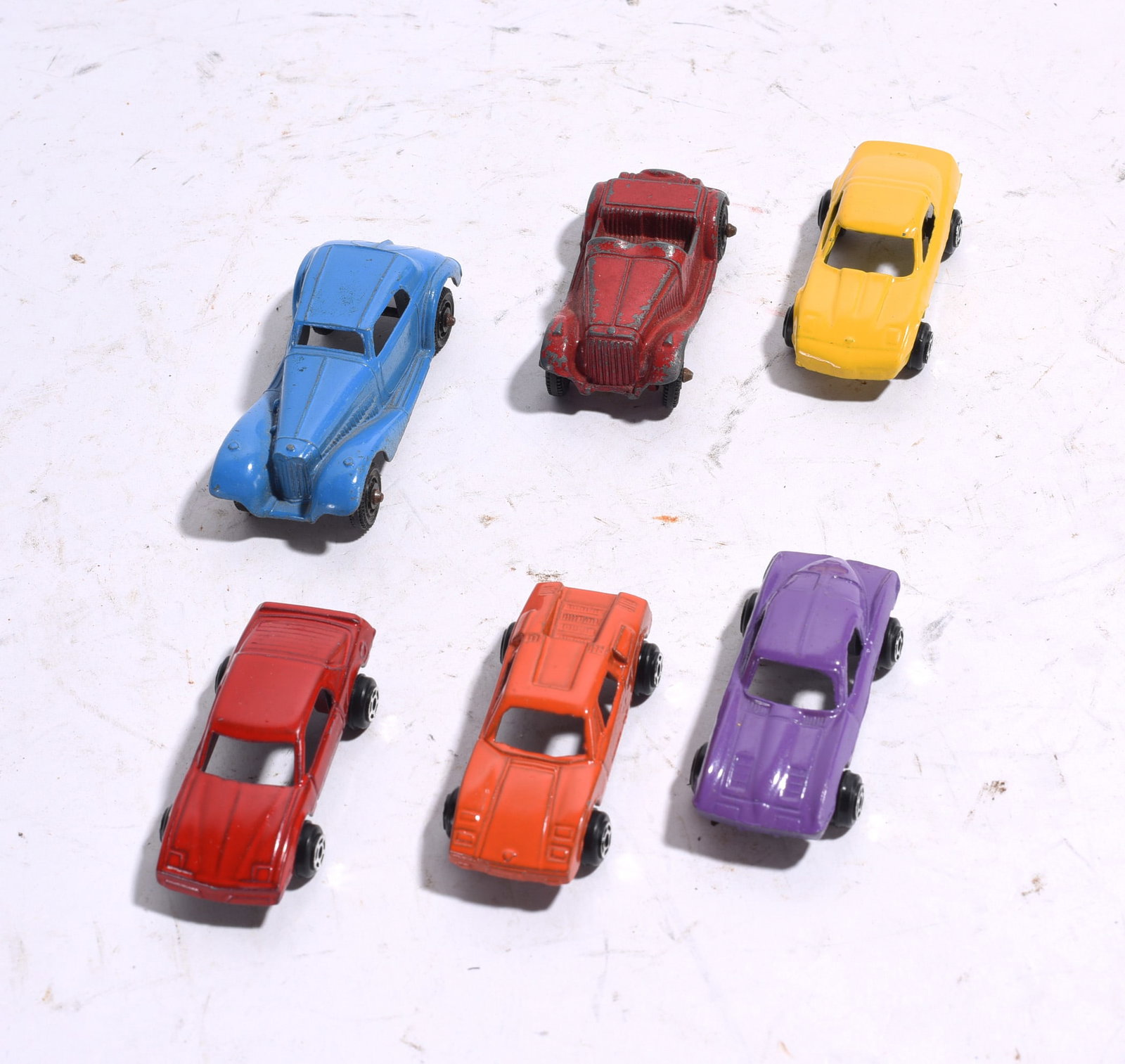 Group of Six Assorted Die-Cast and Plastic Toy Cars: Group of six assorted toy vehicles including die-cast and plastic examples featuring sports cars, coupes, and roadster styles. Displays varying degrees of wear, paint loss, and age-related condition