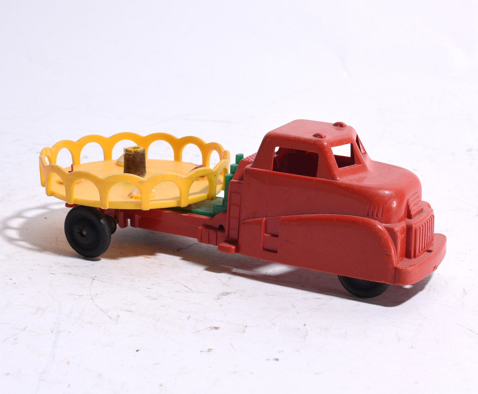 Plastic Stake Bed Truck with Carousel Trailer: Plastic stake bed truck with attached carousel-style trailer accessory. Brightly colored toy retaining original wheels and molded details with minor wear.