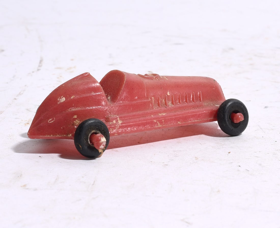Vintage Red Plastic Speedster Race Car: Vintage red plastic speedster race car with streamlined body and open cockpit. Displays minor scuffs and age-related wear.