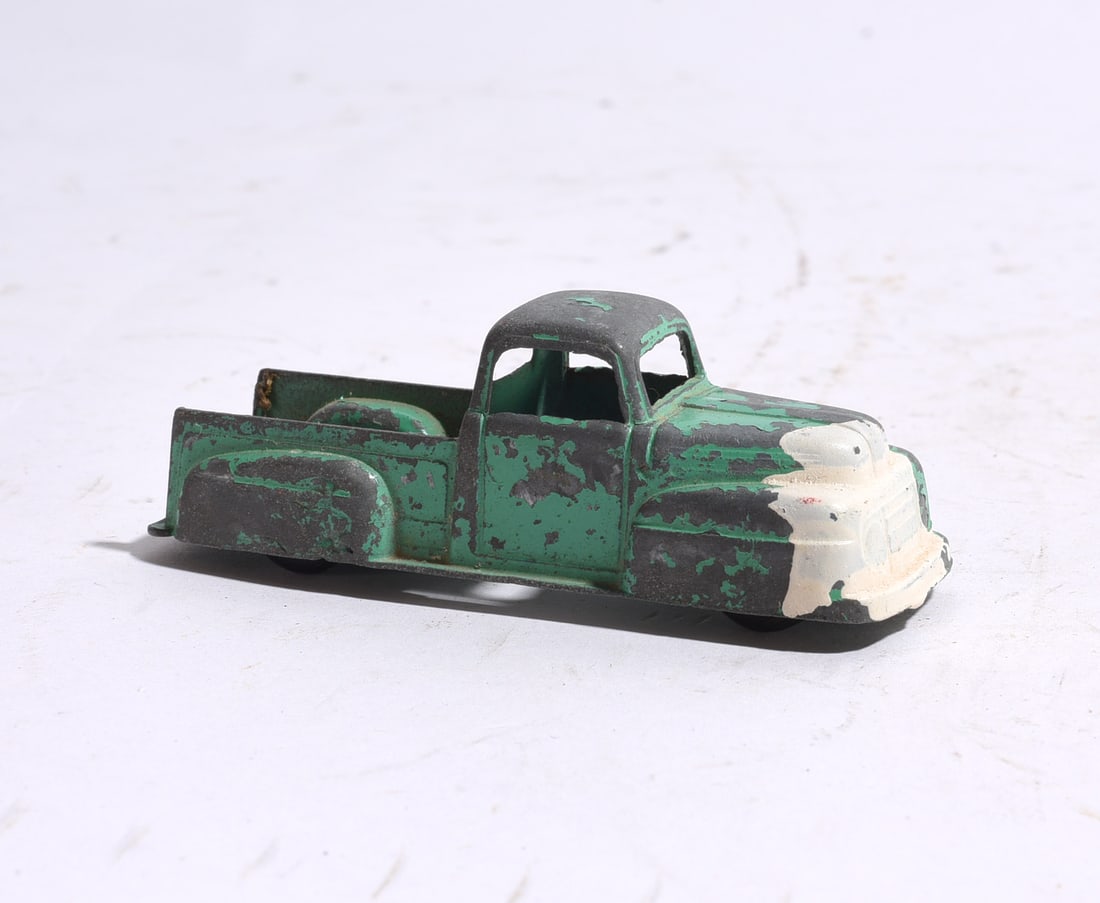 Vintage Die-Cast Green & Cream Pickup Truck: Mid-century die-cast pickup truck featuring green body with cream front end and cargo bed. Exhibits heavy paint wear, surface oxidation, and playwear consistent with age. A classic representation of