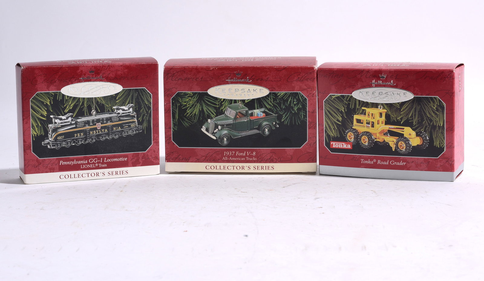 Group of Three Hallmark Keepsake Ornament Collectibles: Group of three Hallmark Keepsake Collector's Series ornaments including Pennsylvania GG-1 Locomotive, 1937 Ford V-8 pickup truck, and Tonka Road Grader examples, all boxed.