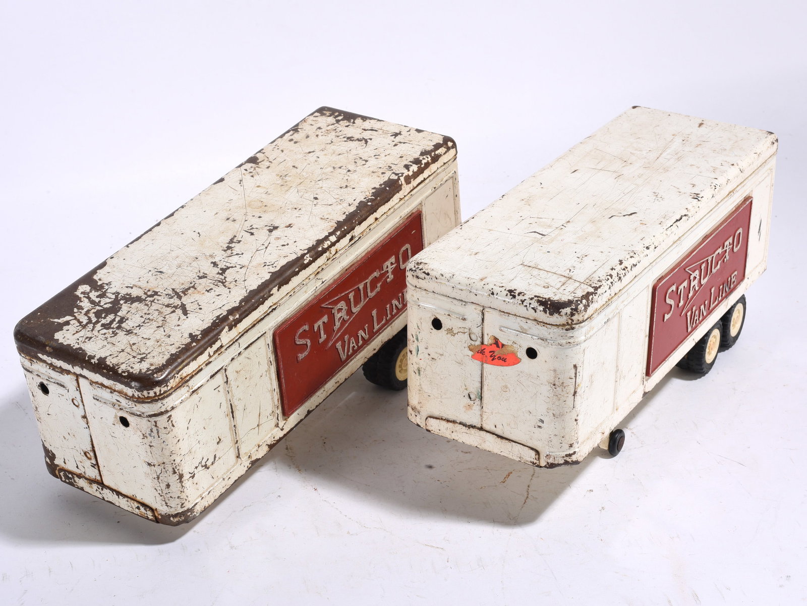 Structo Van Line Trailer Toy Group: Pair of vintage pressed steel Structo Van Line toy trailers with white bodies and red side panels. Both exhibit wear, scratches, and paint loss from use.