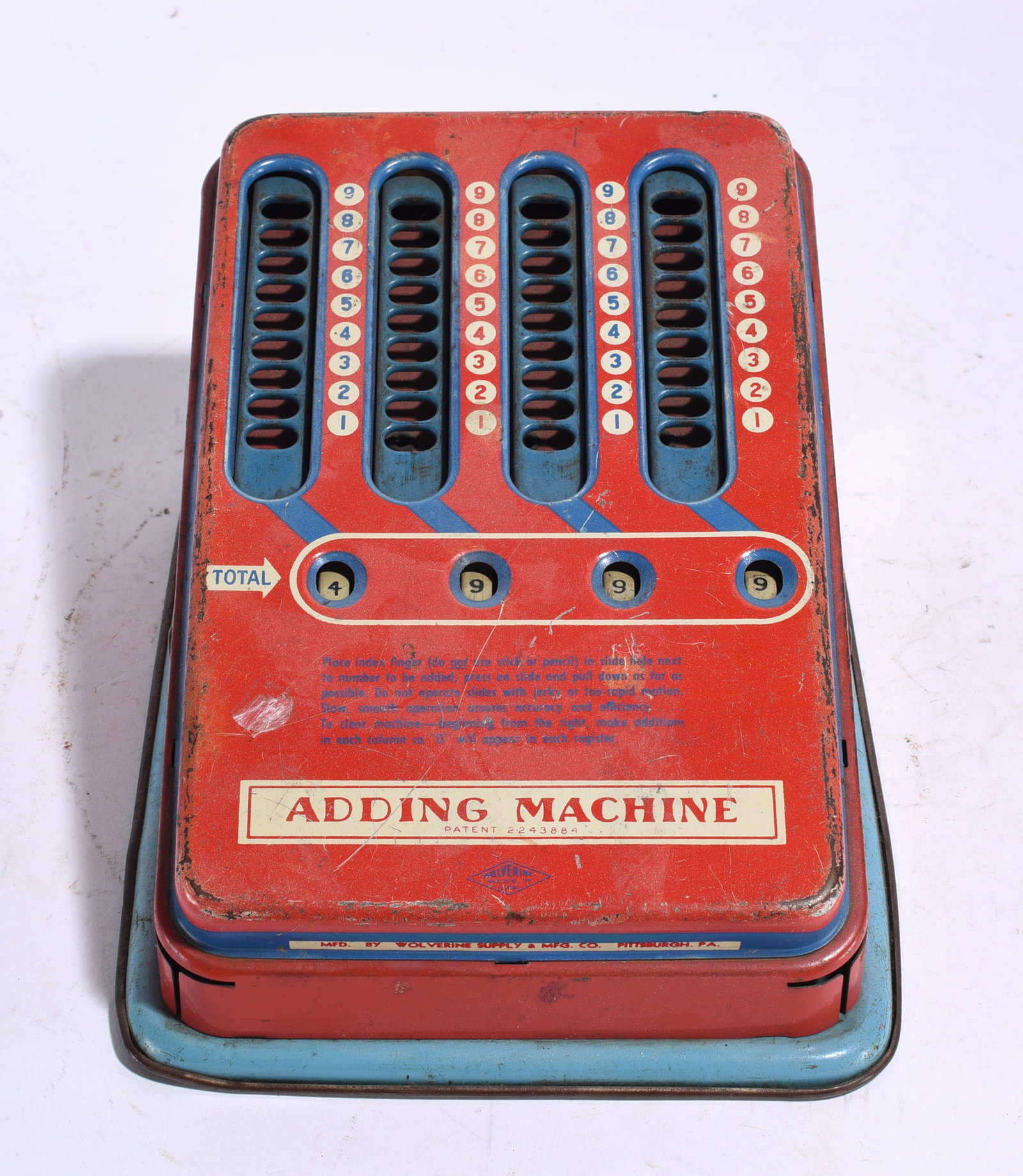 Wolverine Toy Adding Machine: Vintage Wolverine Supply & Mfg. Co. pressed steel toy adding machine in red and blue lithographed finish. Features sliding number registers and original graphics. Wear from age and handling.