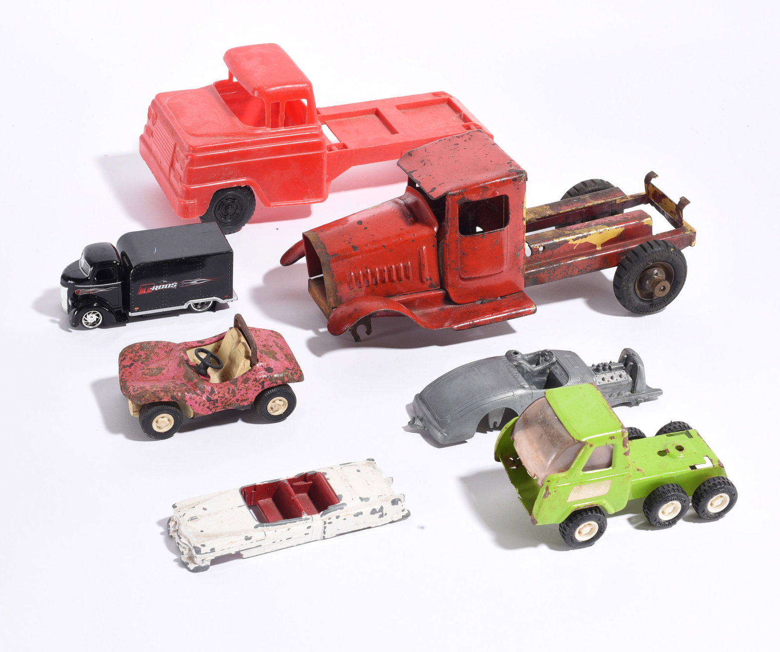 Assorted Toy Vehicle Parts and Trucks: Group of vintage toy trucks, vehicle bodies, chassis parts, and accessories including pressed steel, plastic, and die-cast examples. Offered as found for restoration or display.