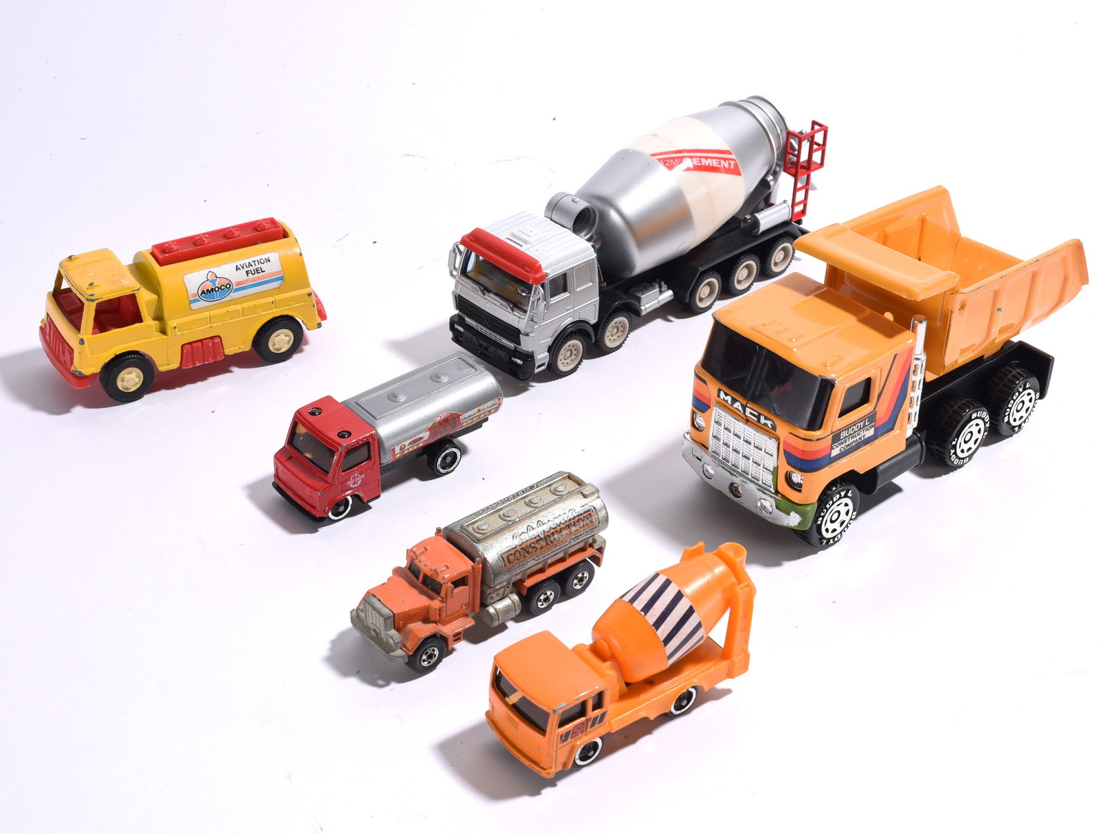 Assorted Construction and Utility Toy Trucks: Collection of die-cast and plastic construction, fuel, and utility trucks including Mack dump truck, cement mixers, fuel tankers, and service vehicles. Mixed manufacturers and scales.