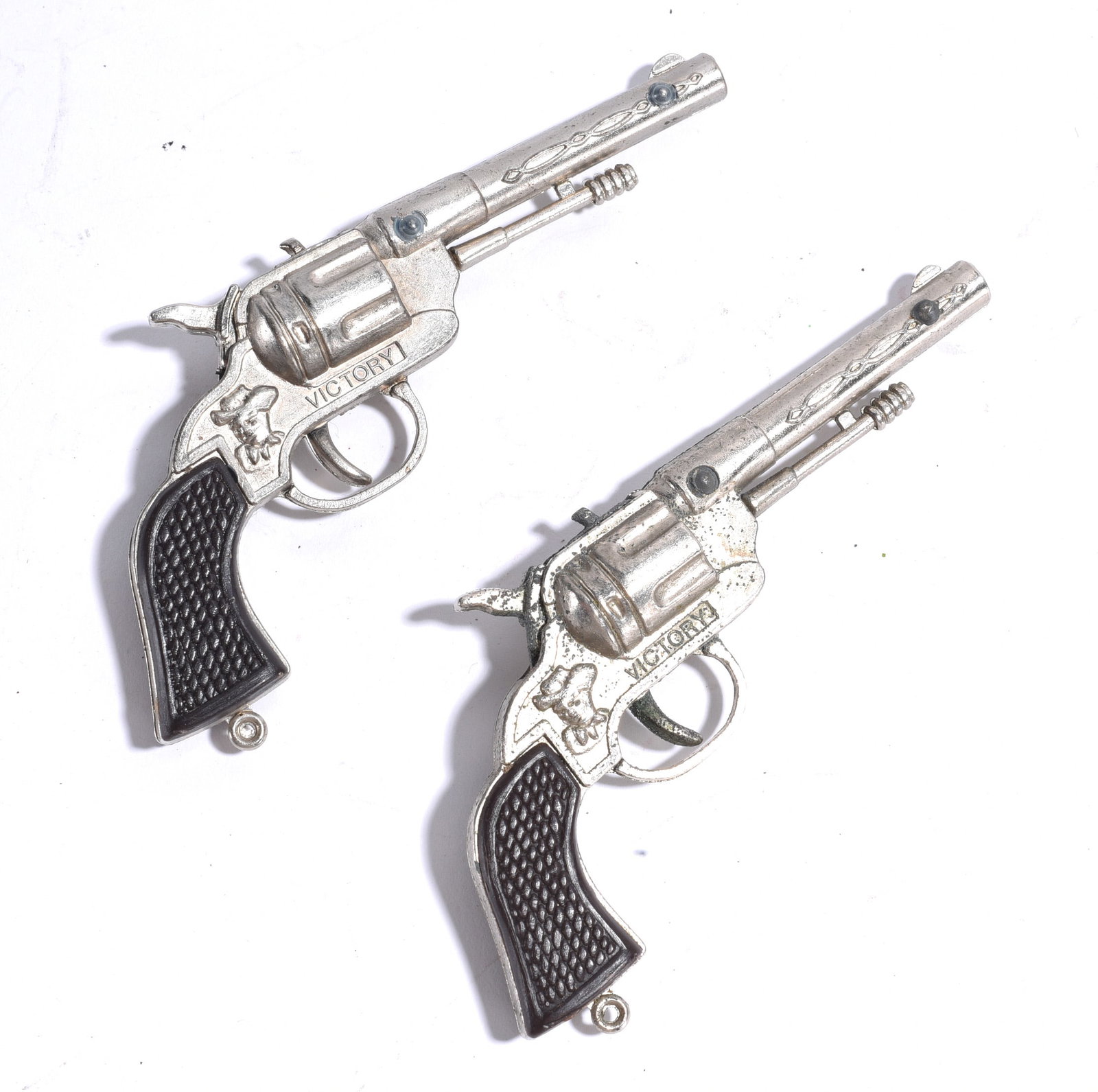 Pair of Victory Cap Pistols: Pair of vintage Victory cap pistols with silver-tone finish and black grips. Decorative western-style toy revolvers showing minor wear from age and handling.
