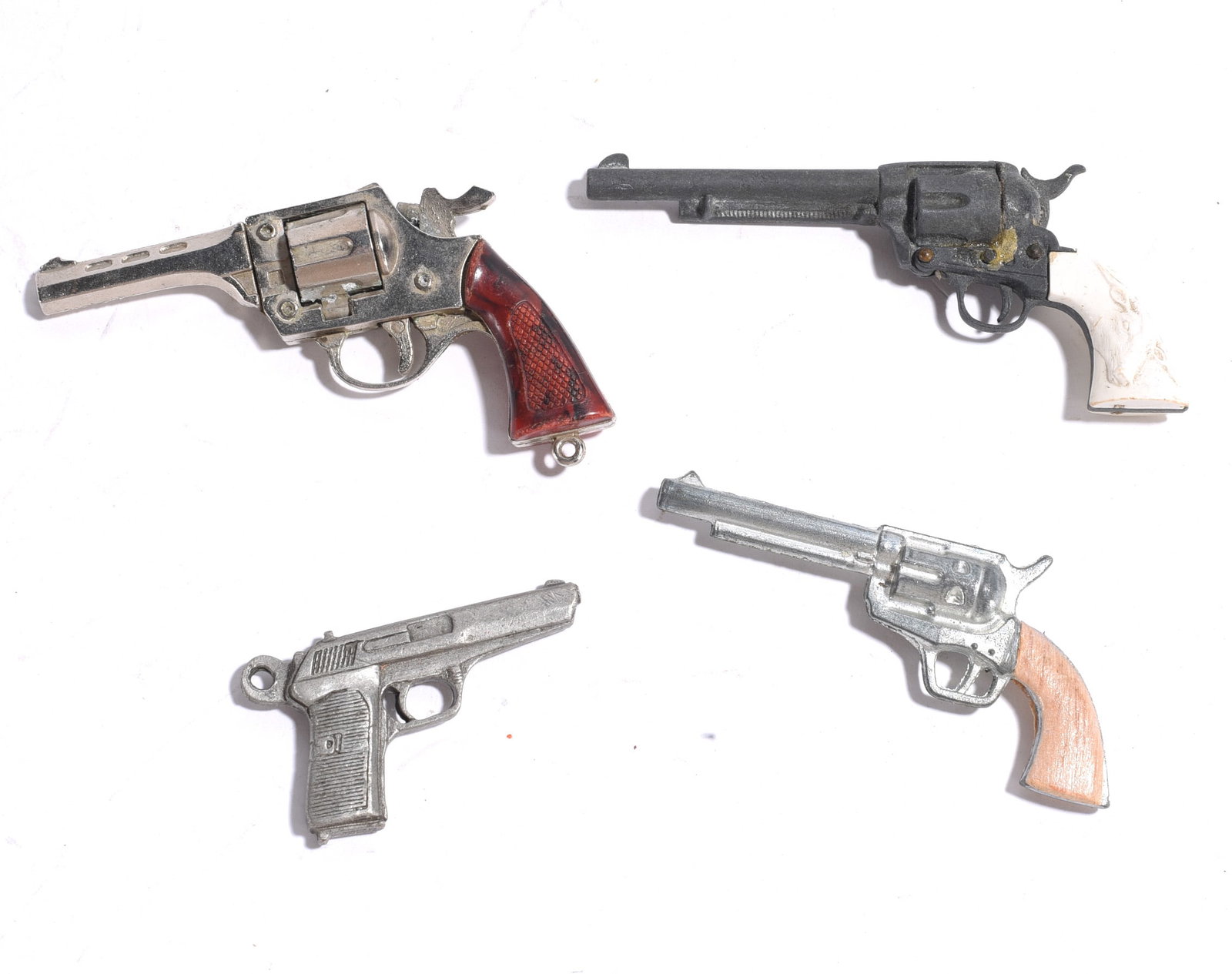 Assorted Toy Cap Pistols: Collection of four miniature toy pistols including western revolvers and automatic pistol examples. Mixed materials and finishes with wear from age and handling.