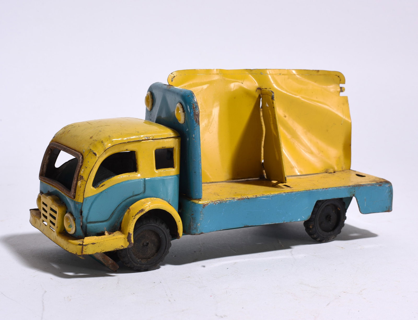 Pressed Steel Utility Truck: Vintage pressed steel utility truck in blue and yellow painted finish with rear compactor or service body. Surface wear, paint loss, and oxidation consistent with age.