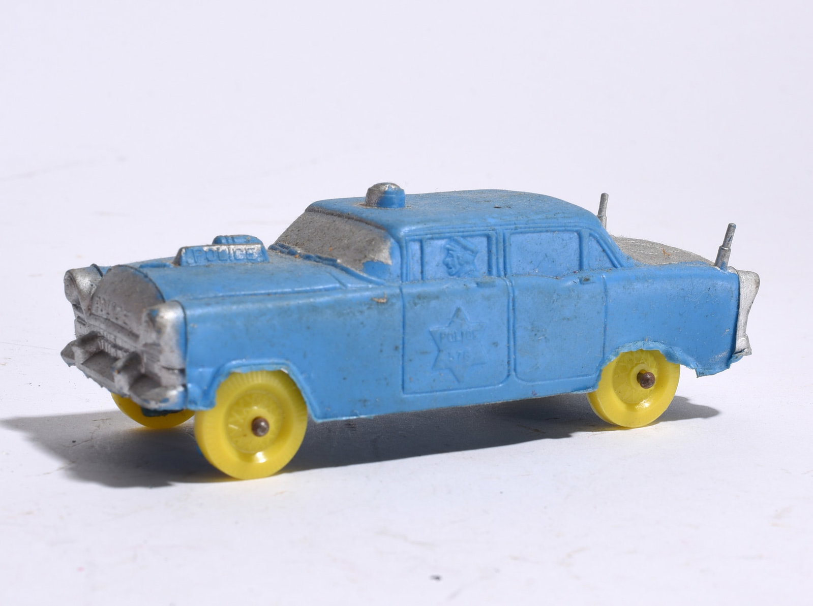 Plastic Toy Police Car: Plastic toy police sedan with blue body, yellow wheels, and molded officer figure. Retains police markings and roof light detail. Light wear from use.
