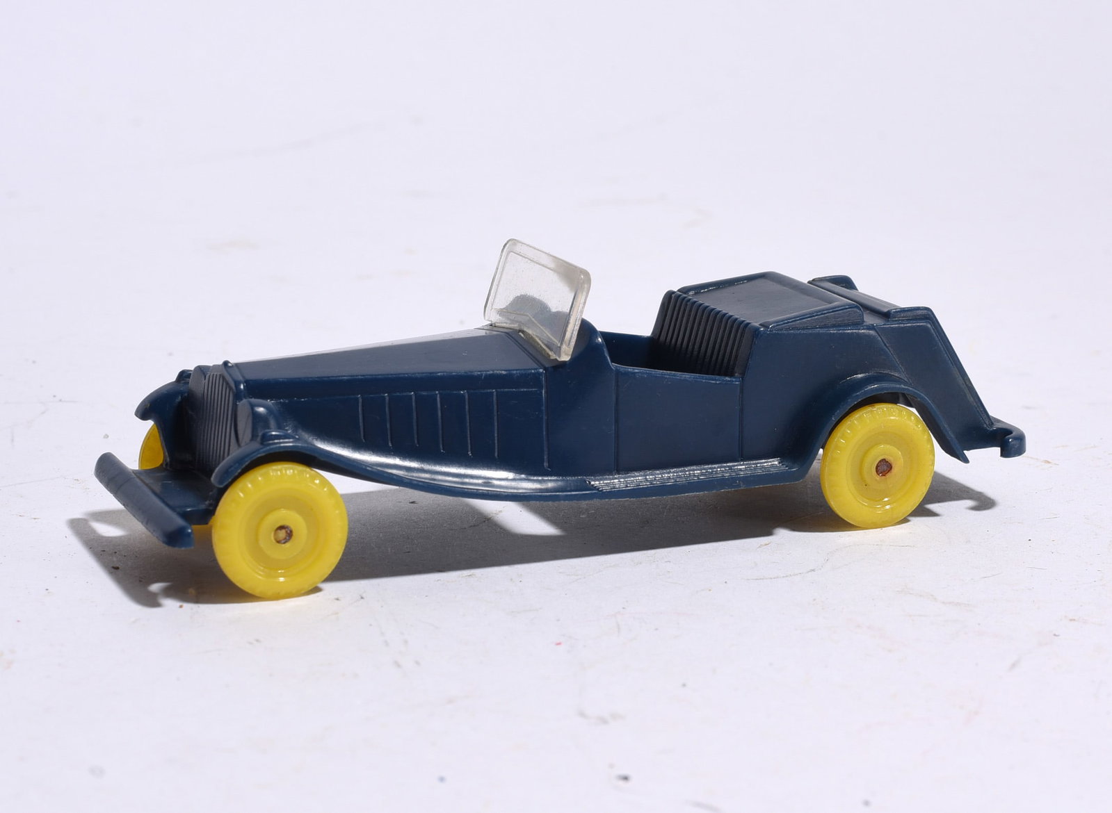 Plastic Convertible Automobile: Vintage molded plastic convertible automobile in dark blue finish with yellow wheels and clear windshield. Good display example with light handling wear.