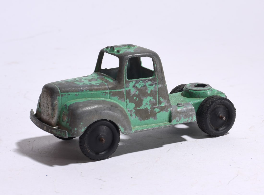Cast Metal Truck Tractor: Cast metal truck tractor with remnants of green paint and original wheels. Offered as found with wear consistent with age and use.