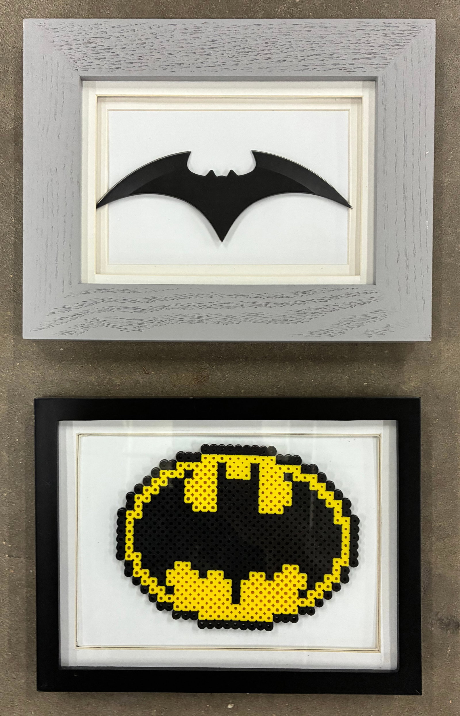Batman-Themed Framed Wall Art Pair: 9"x7" each Pair of framed Batman-themed decorative wall art pieces including a black bat emblem shadowbox and pixel-style Batman logo artwork. Sold together as one lot.