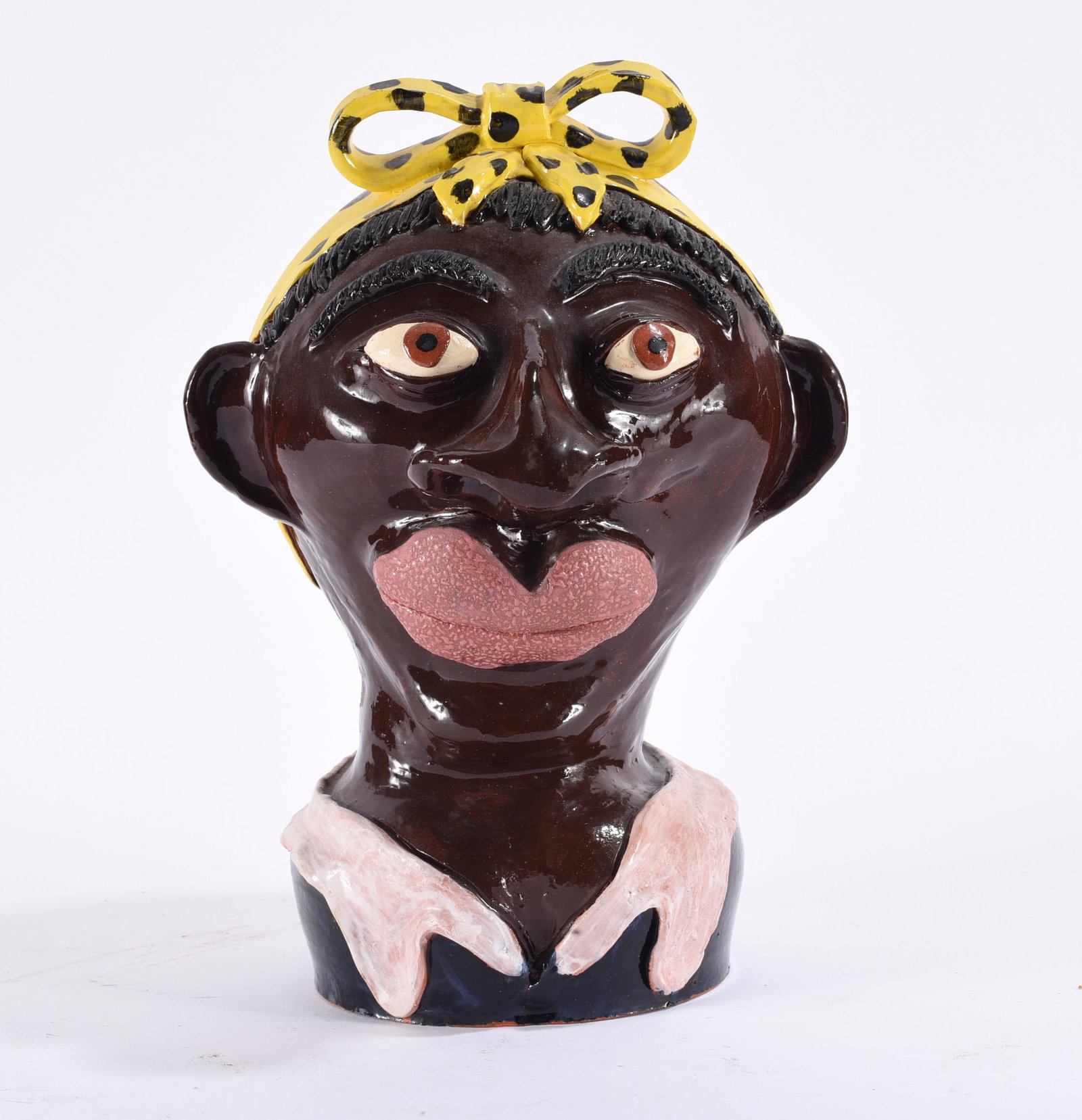 Albert Hodge Folk Pottery Figural: 13" Expressive folk pottery bust with glossy dark glaze, large sculpted eyes and lips, applied ears, yellow patterned head bow and contrasting clothing details.
