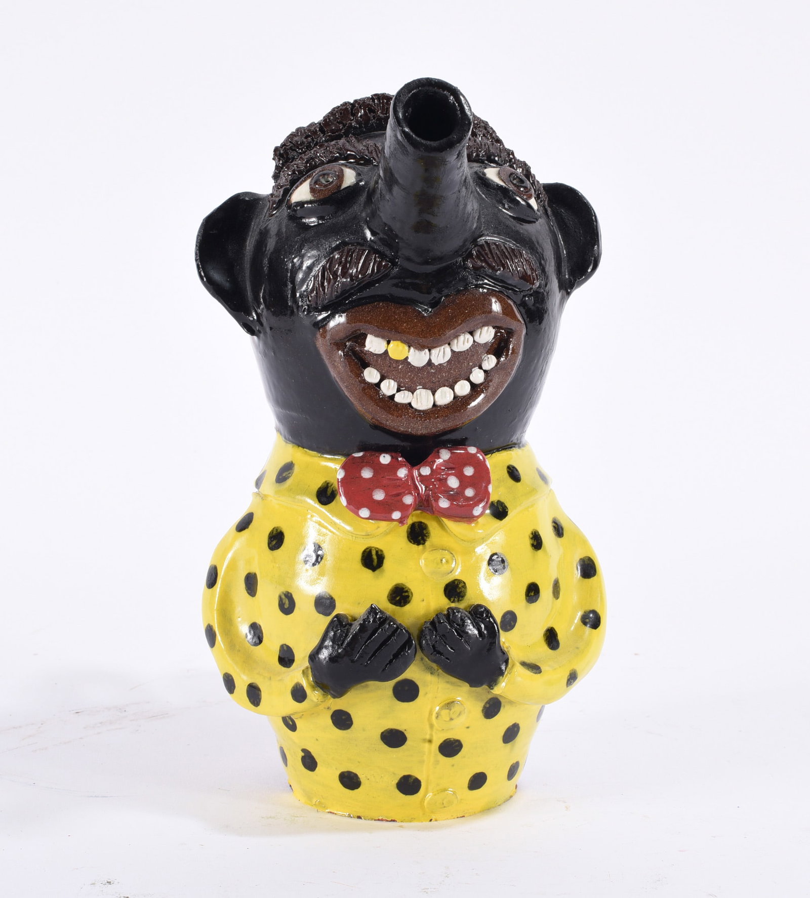 Albert Hodge Folk Pottery Figural: 9" Whimsical figural folk pottery vessel with elongated spout nose, wide tooth-filled grin, red polka-dot bow tie and bright yellow polka-dot shirt.