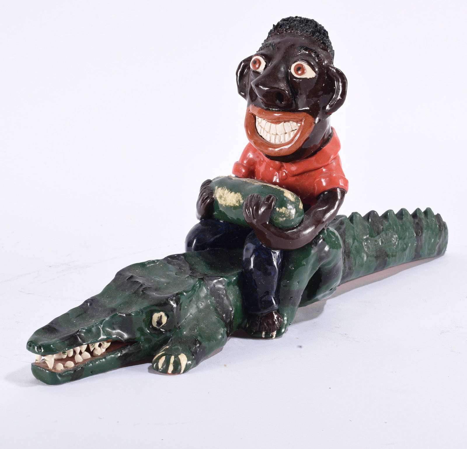 Albert Hodge Folk Pottery Figural: 9"x19" Whimsical folk pottery figural depicting a smiling rider seated atop a long green alligator, with modeled teeth, claws and expressive facial details.