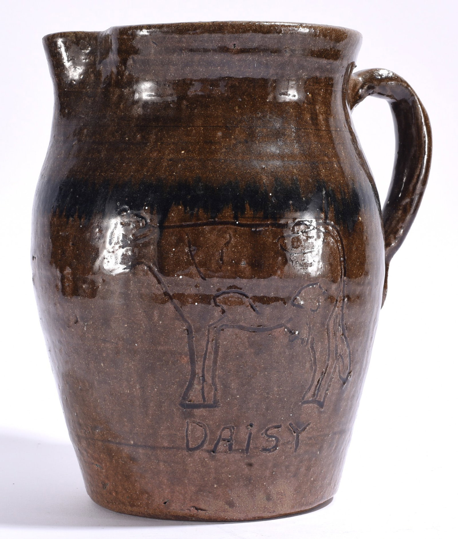 Chester Hewell Folk Pottery: 10" Chester Hewell folk pottery pitcher with rich brown glaze, applied handle and incised decoration depicting figures and the word "DAISY." Hewell was part of the important north Georgia pottery trad
